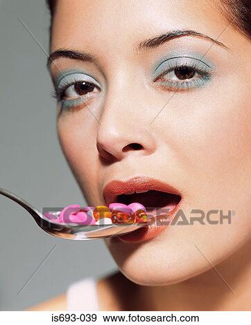 Woman eating spoon of tablets View Large Photo Image Stock Photo - Woman eating spoon of tablets. Fotosearch
