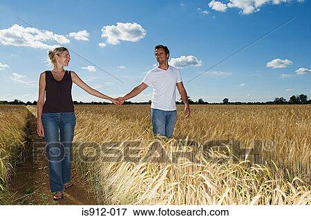 Couple holding hands in a field View Large Photo Image Stock Photo - Couple holding hands in a field. Fotosearch