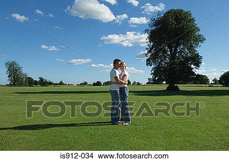 Picture - Couple hugging in a field. Fotosearch