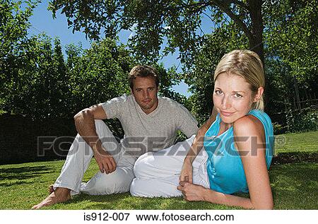 Couple relaxing on the grass View Large Photo Image Stock Photo - Couple relaxing on the grass. Fotosearch