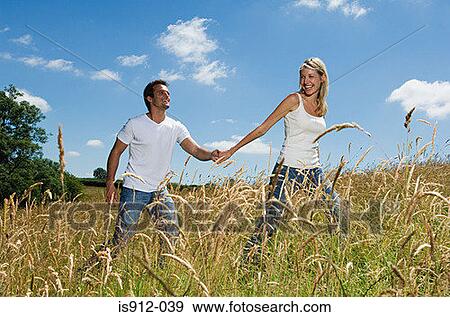 Couple walking through field View Large Photo Image Stock Photo - Couple walking through field. Fotosearch