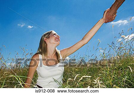 Stock Photo - Woman in field being helped up. Fotosearch