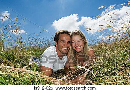 Stock Photography - Young couple lying in a field. Fotosearch