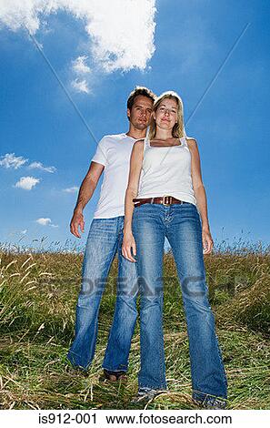 Stock Image - Young couple standing in a field. Fotosearch
