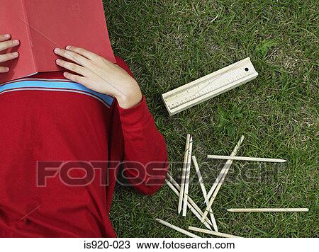 Stock Image - Boy covering his face with a book. Fotosearch