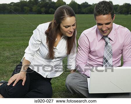 Stock Photo - Couple using a laptop computer in the park. Fotosearch