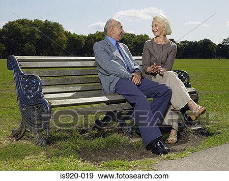 Stock Photo - Elderly couple sitting on a park bench. Fotosearch
