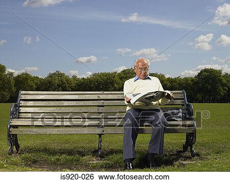 Elderly man reading a newspaper in a park View Large Photo Image Stock Photograph - Elderly man reading a newspaper in a park. Fotosearch