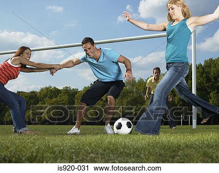 Stock Image - Friends playing football in the park. Fotosearch