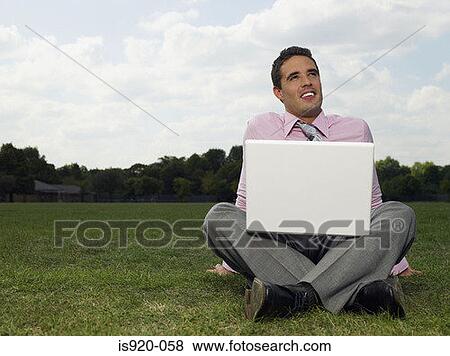Stock Photo - Man using a laptop computer in a park. Fotosearch