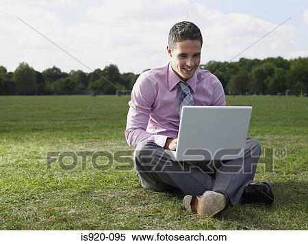 Stock Photography - Man using a laptop computer in a park. Fotosearch