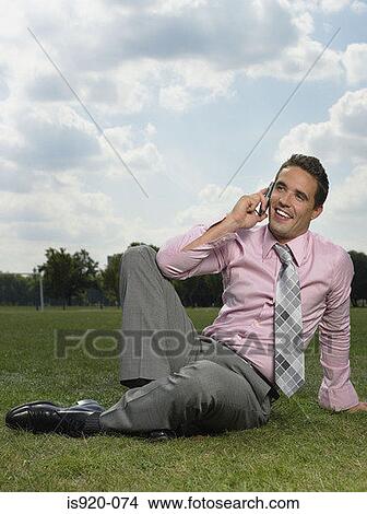 Picture - Man using his cellular telephone in park. Fotosearch