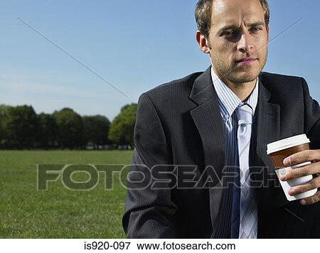Serious looking businessman in a park View Large Photo Image Stock Photo - Serious looking businessman in a park. Fotosearch