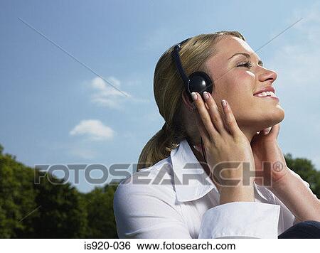 Woman listening to music in a park View Large Photo Image Stock Photograph - Woman listening to music in a park. Fotosearch
