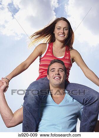 Stock Photo - Young man shoulder carrying a woman. Fotosearch