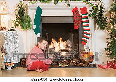 Picture - Boy sitting by fireplace at christmas. Fotosearch