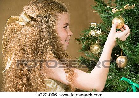 Stock Photograph - Girl decorating a christmas tree. Fotosearch