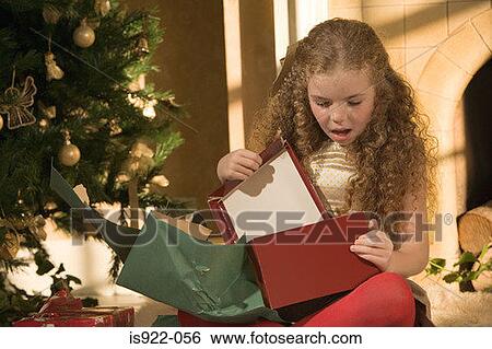 Stock Photograph - Girl opening christmas presents. Fotosearch