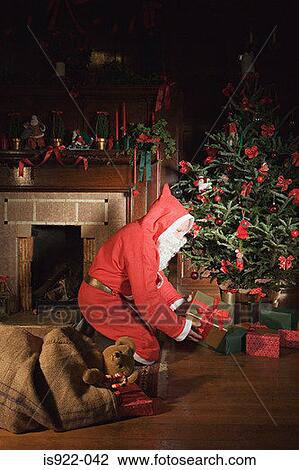 Santa claus placing presents under christmas tree View Large Photo Image Stock Image - Santa claus placing presents under christmas tree. Fotosearch