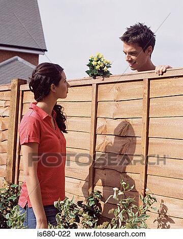 Stock Image - Man and woman talking over garden fence. Fotosearch