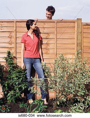 Man looking over fence at woman View Large Photo Image Picture - Man looking over fence at woman. Fotosearch