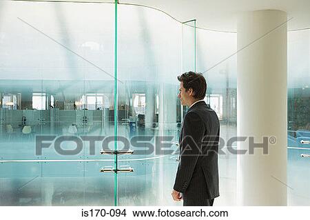 Businessman looking into office View Large Photo Image Picture - Businessman looking into office. Fotosearch
