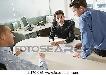 Stock Photography - Businessmen discussing document. Fotosearch