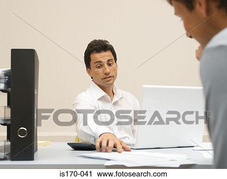 Stock Image - Colleagues discussing paperwork. Fotosearch