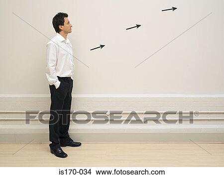 Man looking at arrows on a wall View Large Photo Image Picture - Man looking at arrows on a wall. Fotosearch