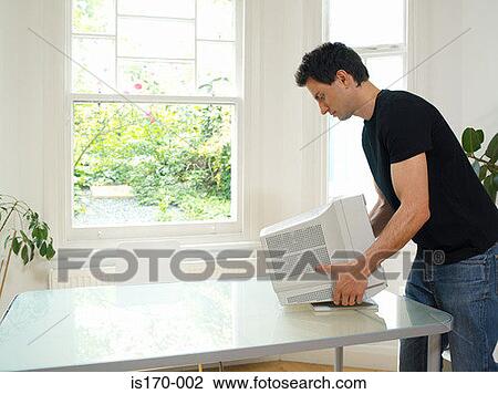 Stock Image - Man moving computer monitor. Fotosearch