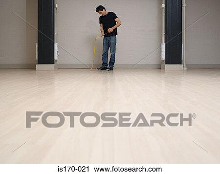 Man with tape measure in empty office space View Large Photo Image Stock Image - Man with tape measure in empty office space. Fotosearch
