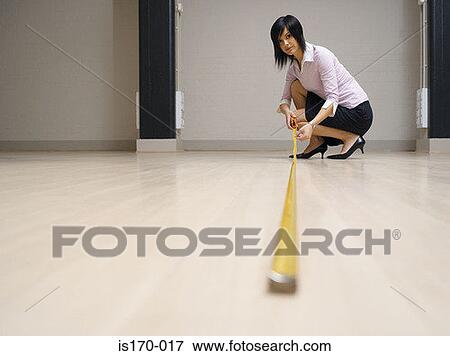 Stock Photo - Woman measuring floor. Fotosearch