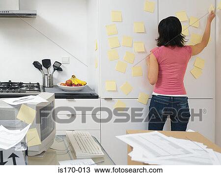 Woman putting up adhesive notes in the kitchen View Large Photo Image Stock Image - Woman putting up adhesive notes in the kitchen. Fotosearch