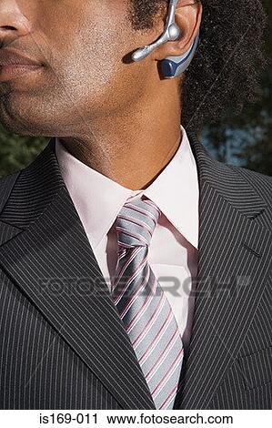 Stock Image - Businessman wearing a bluetooth headset. Fotosearch