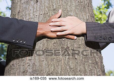 Stock Photography - Businesspeople hugging a tree. Fotosearch