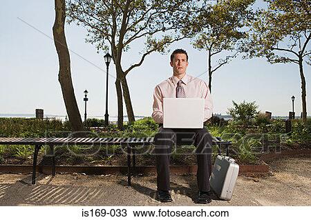 Stock Image - Man telecommuting in a park. Fotosearch