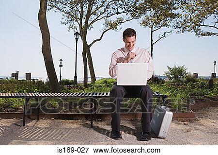 Stock Photo - Man telecommuting in a park. Fotosearch