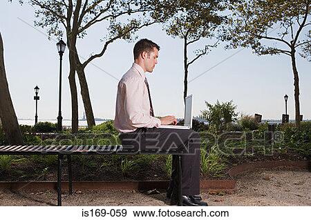 Man telecommuting in a park View Large Photo Image Stock Photo - Man telecommuting in a park. Fotosearch