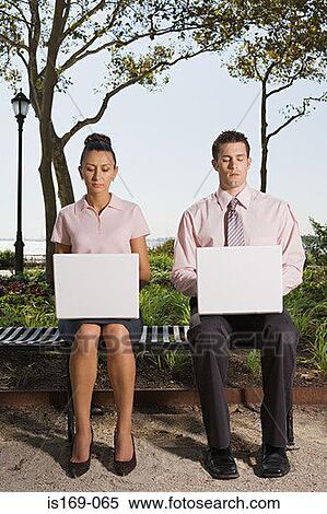 Stock Photography - Two people telecommuting in a park. Fotosearch
