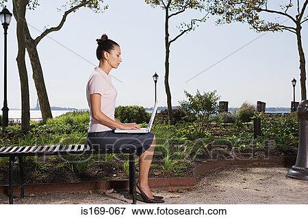 Woman telecommuting in a park View Large Photo Image Stock Photo - Woman telecommuting in a park. Fotosearch