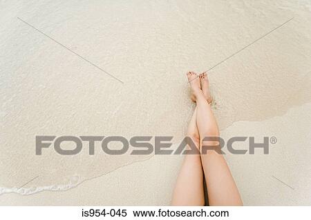 Stock Photography - Legs of woman reclining on beach. Fotosearch