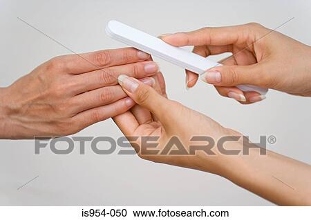 Stock Image - Woman having nails filed. Fotosearch