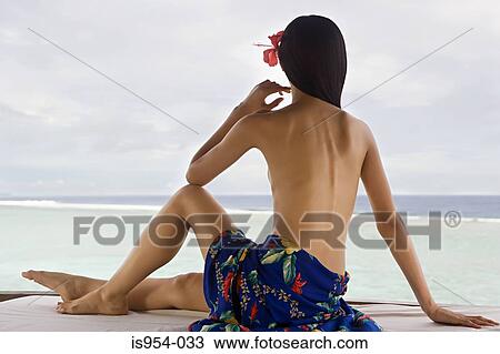 Stock Image - Woman relaxing by ocean. Fotosearch