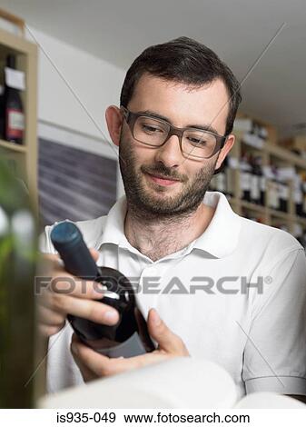 Bearded and bespectacled man holding wine bottle View Large Photo Image Stock Photo - Bearded and bespectacled man holding wine bottle. Fotosearch