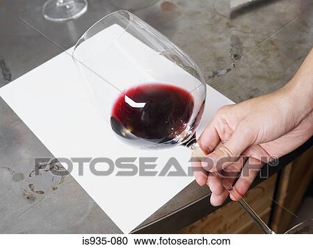 Stock Image - Checking colour of red wine against white paper. Fotosearch