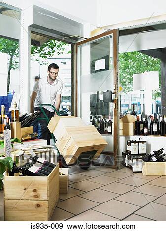 Man pushing trolley of wine boxes into shop View Large Photo Image Stock Photo - Man pushing trolley of wine boxes into shop. Fotosearch