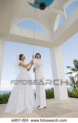 Picture - Bride and groom ringing church bell. Fotosearch