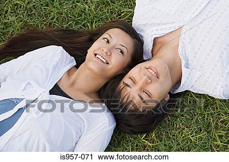 Couple relaxing on grass View Large Photo Image Stock Image - Couple relaxing on grass. Fotosearch