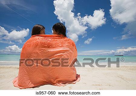 Couple wrapped in shawl on beach View Large Photo Image Stock Image - Couple wrapped in shawl on beach. Fotosearch