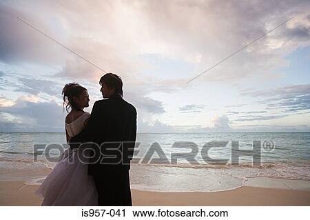 Stock Image - Newlyweds on beach at sunset. Fotosearch